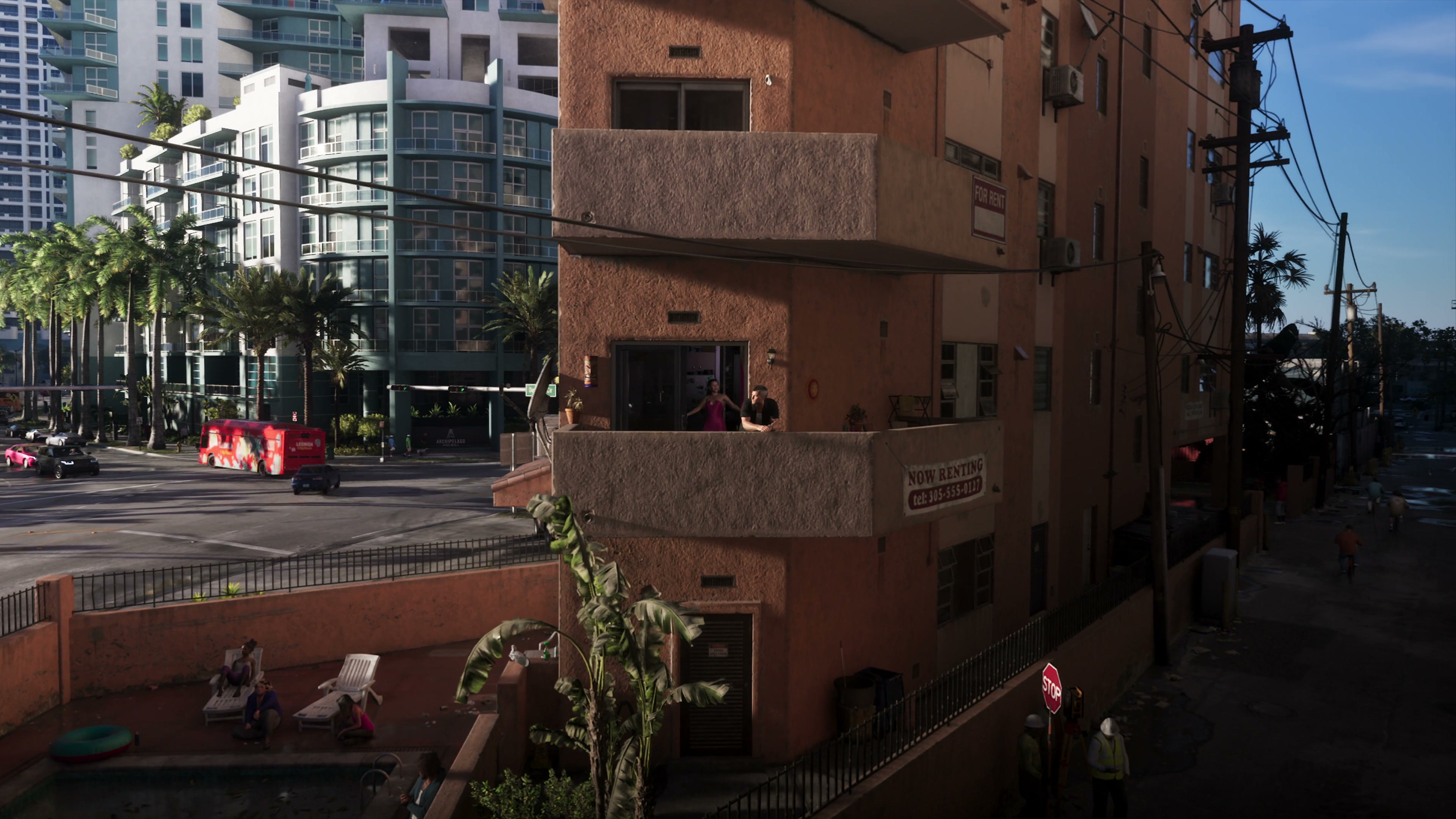 Apartment building with a pool, palm trees, and two people on a balcony.