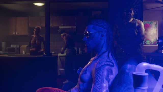 Tattooed woman seated in a blue-lit nightclub.