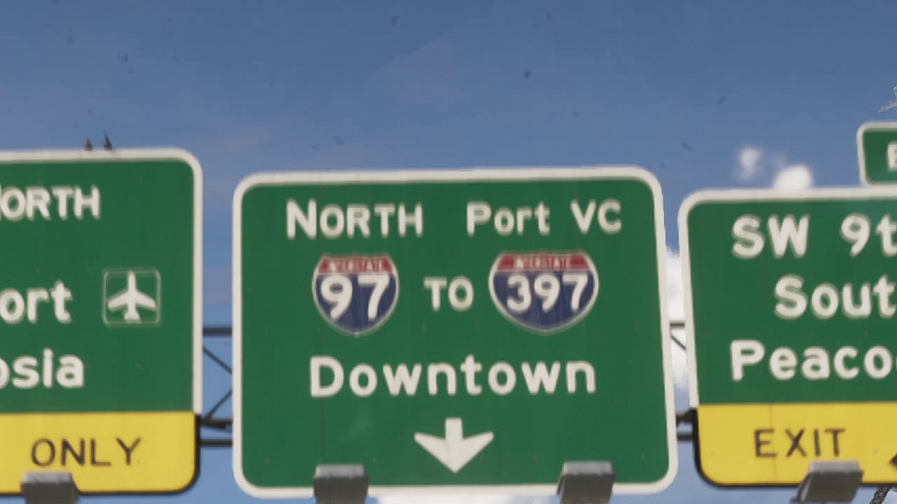 Green "North Port VC, 97 to 397, Downtown" sign on a highway gantry