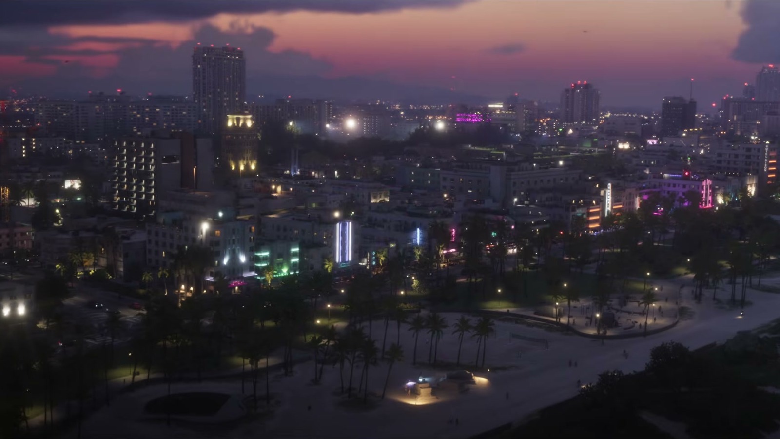 Night aerial of the city, with lit parks and palms.