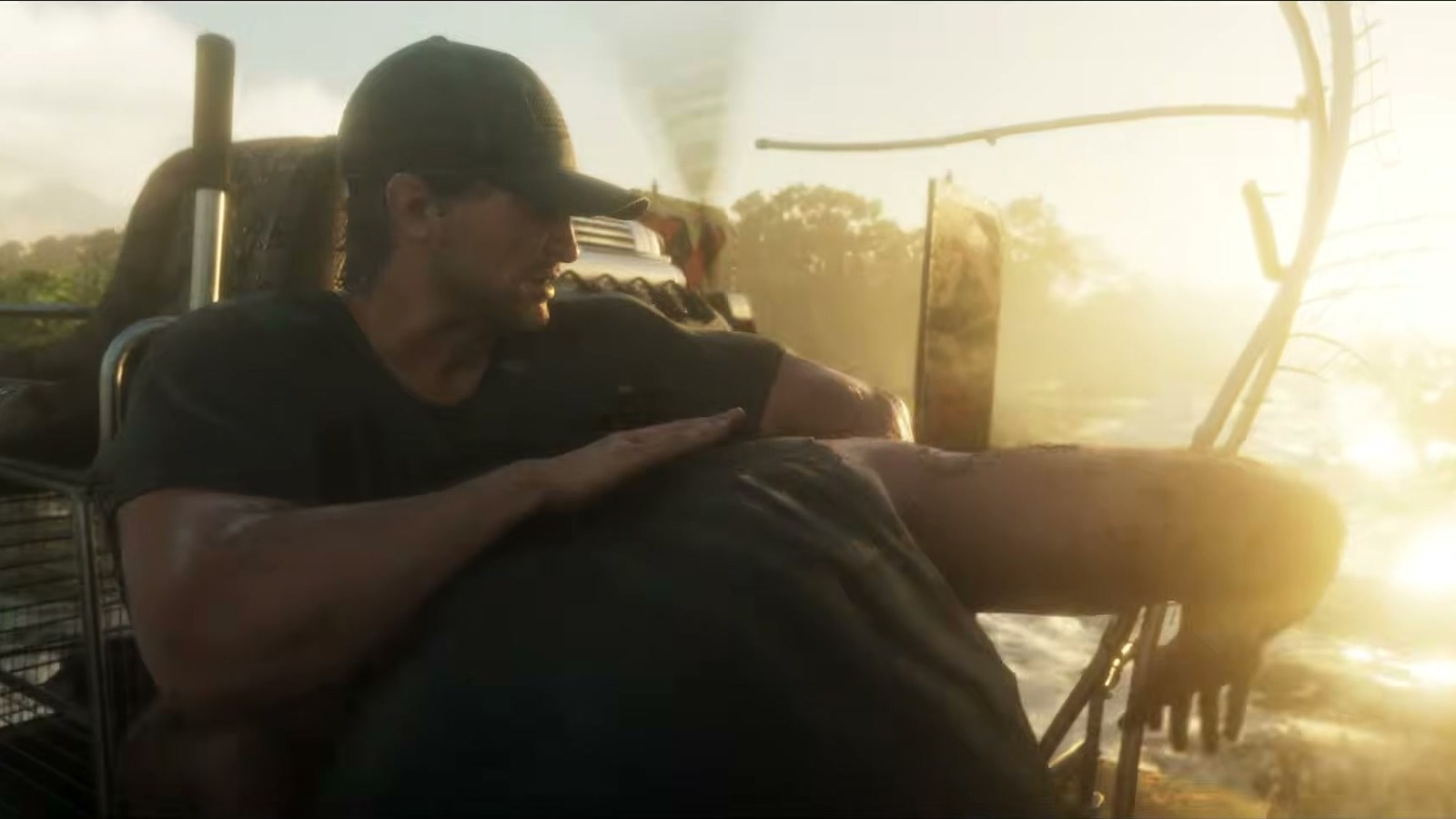 A man in a cap on the raised seat of an airboat, fan cage visible and backlit spray.
