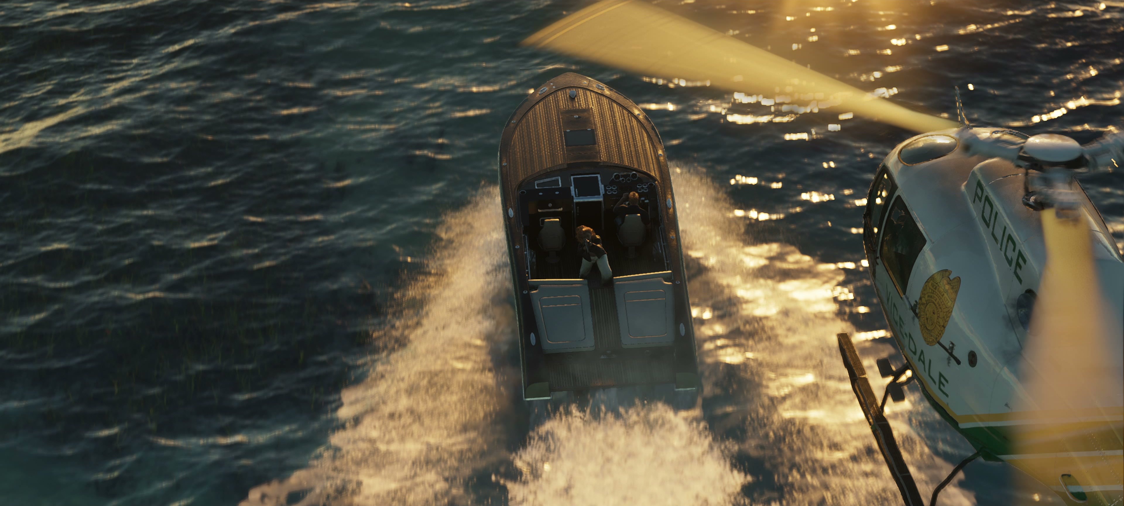 White and green Vice-Dale Police helicopter over a speedboat fleeing across the sea at sunset