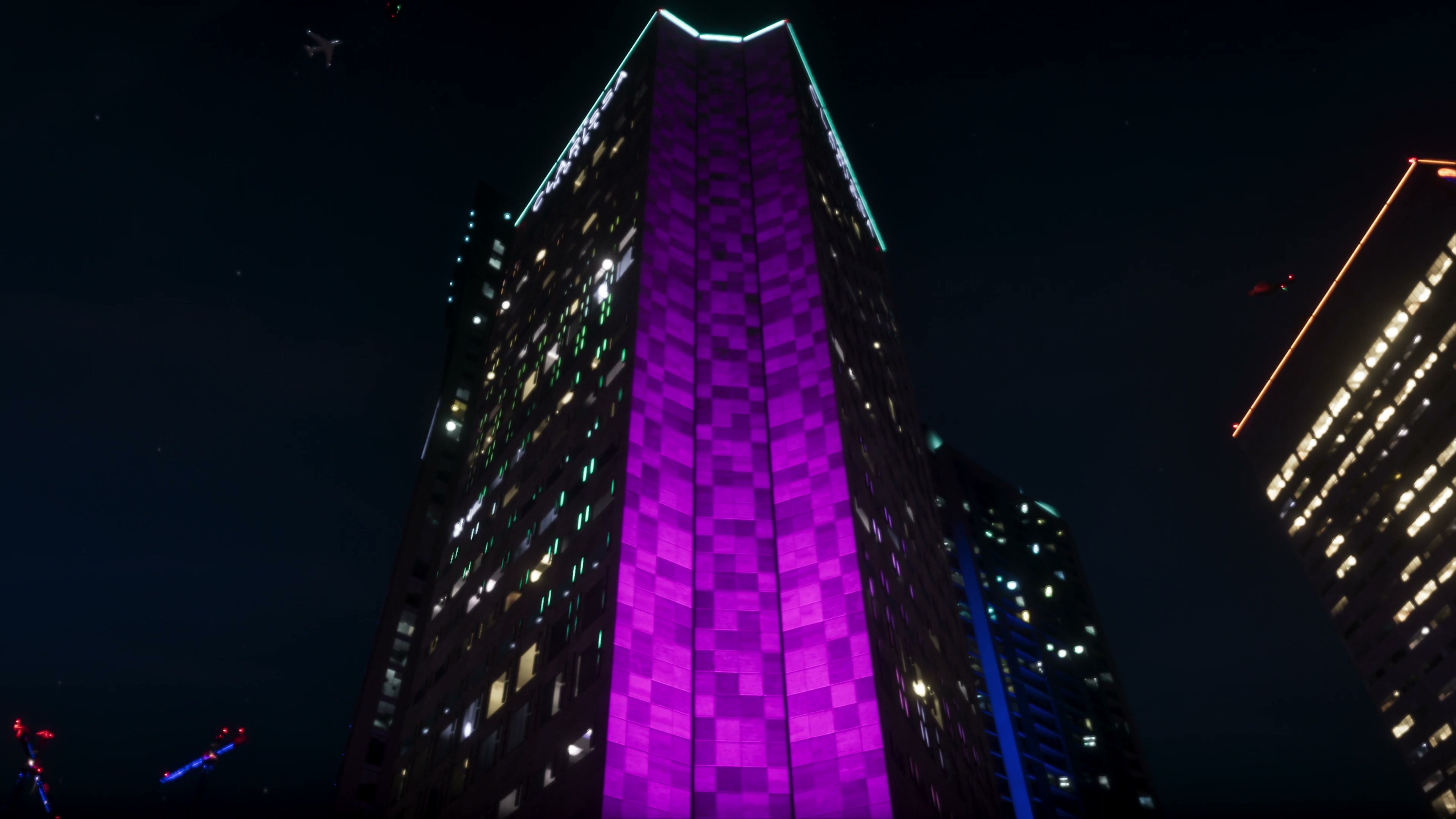 Violet-lit exterior of a hotel at night.