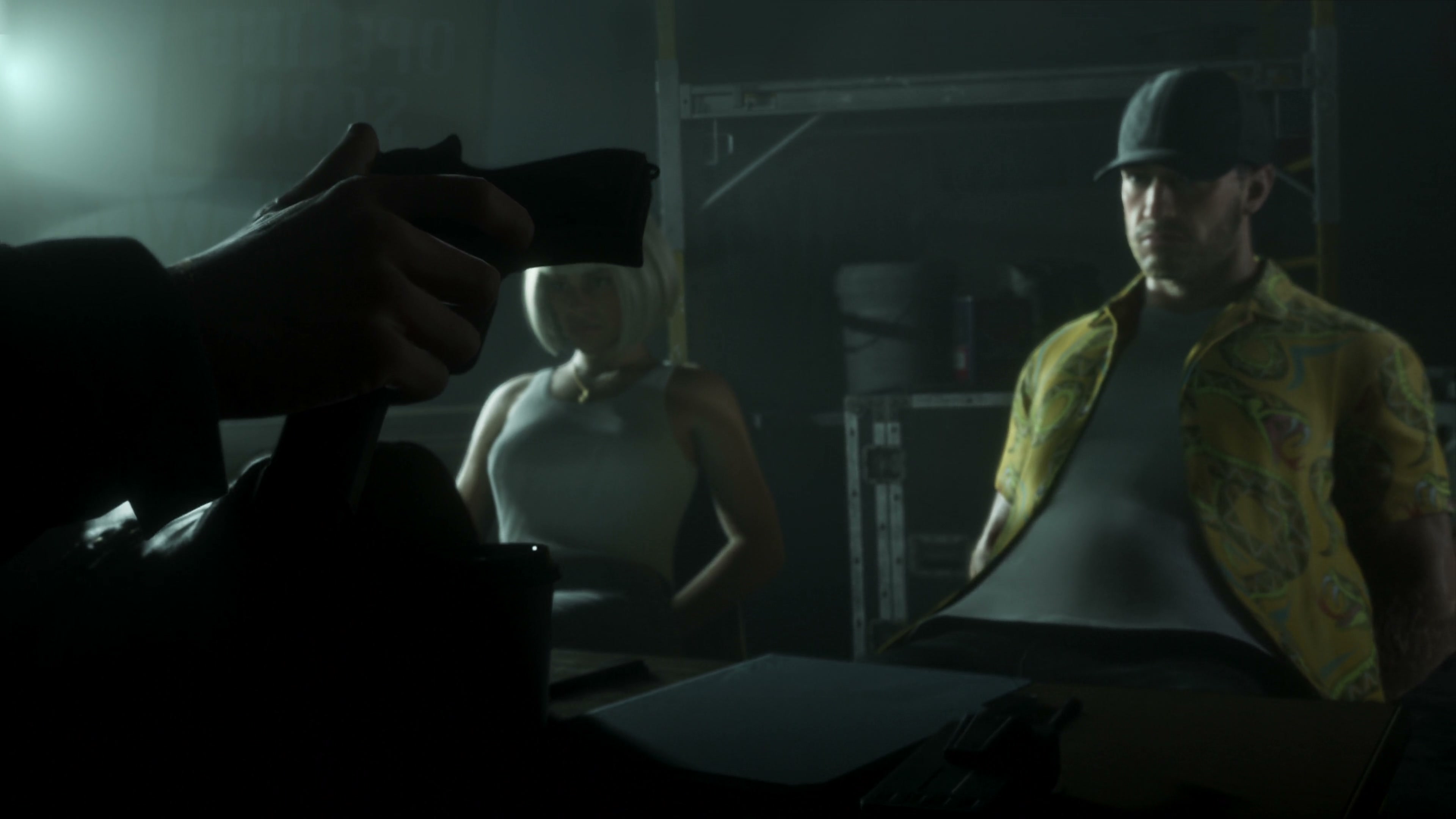 A man wearing a cap points a gun inside a dark room.