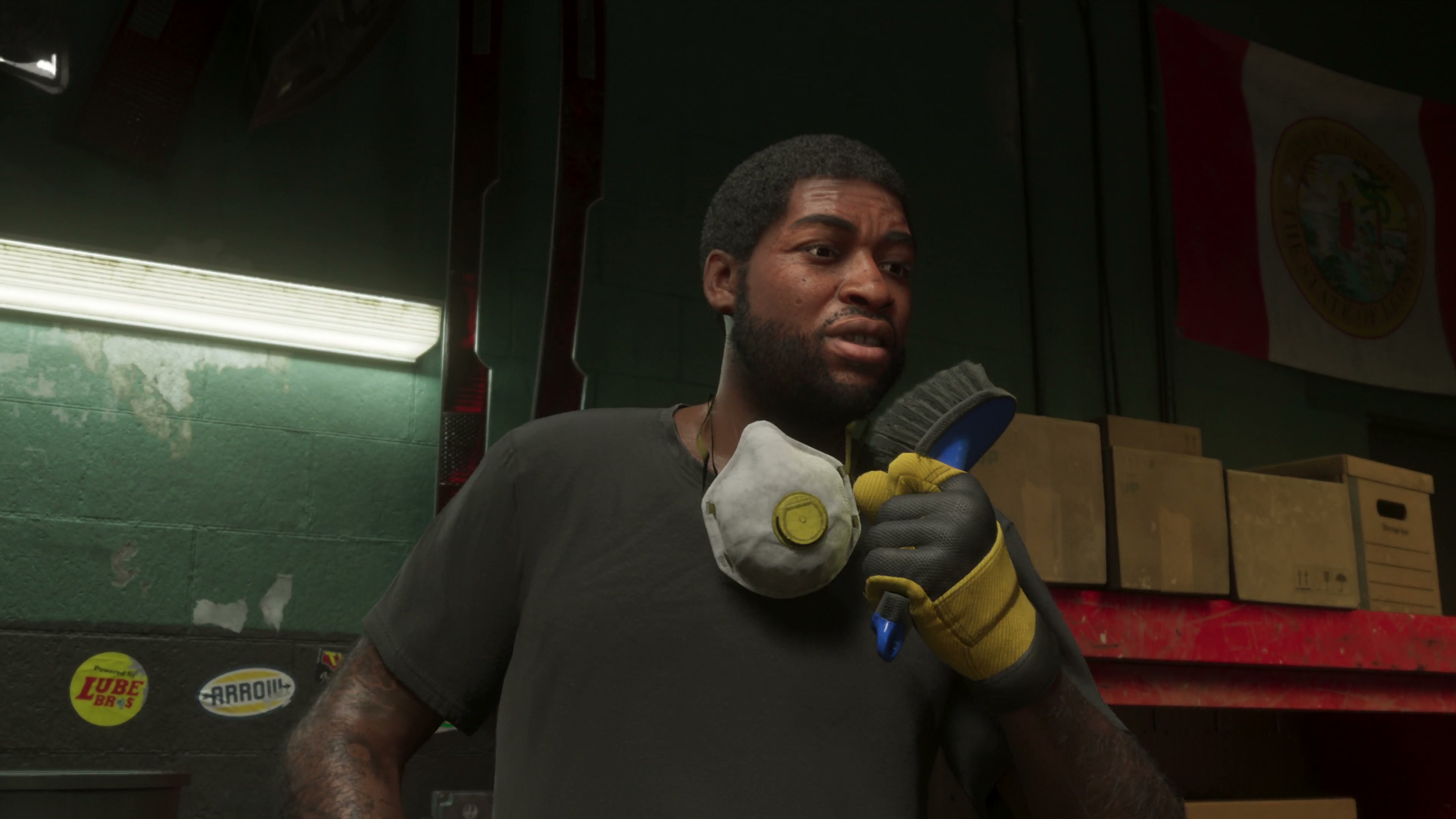 Man wearing a tool backpack beside a vehicle inside a workshop.