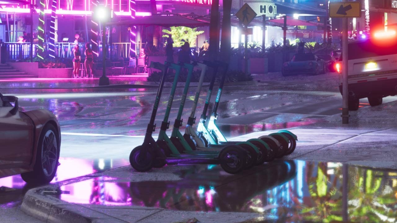 A row of green and black ZOOT rental e-scooters parked on the wet sidewalk outside the Ocean View Hotel at night