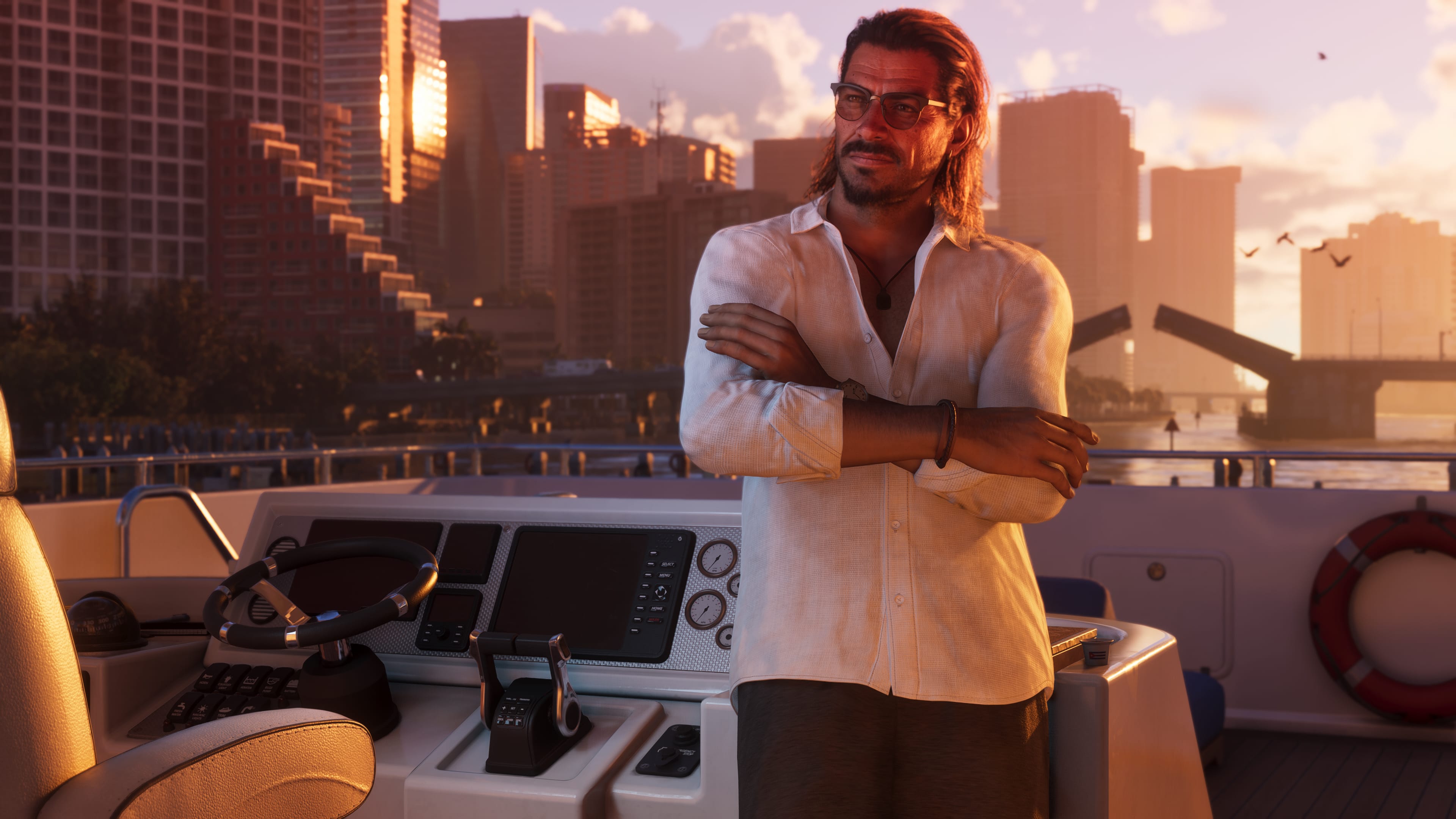 Man with glasses and a white shirt, arms crossed, on a yacht helm; skyline and a drawbridge at sunset.