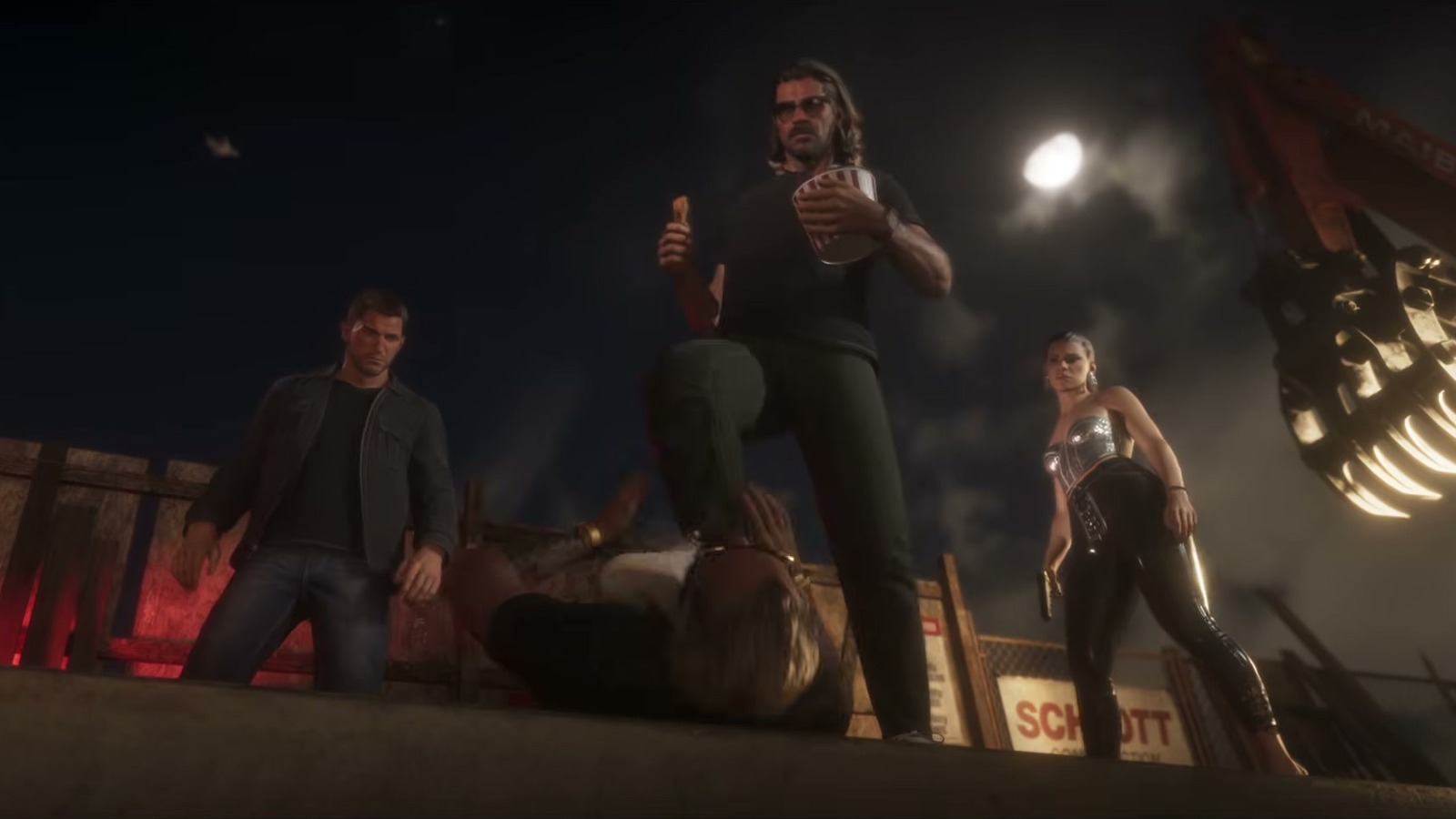 A man in sunglasses stands over someone on the ground on a construction rooftop at night.