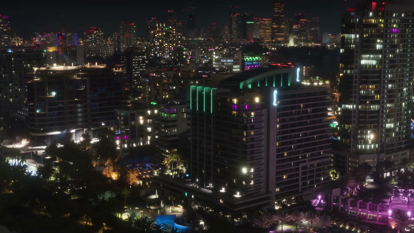 Night aerial of high-rises with green and magenta neon and a lit pool.