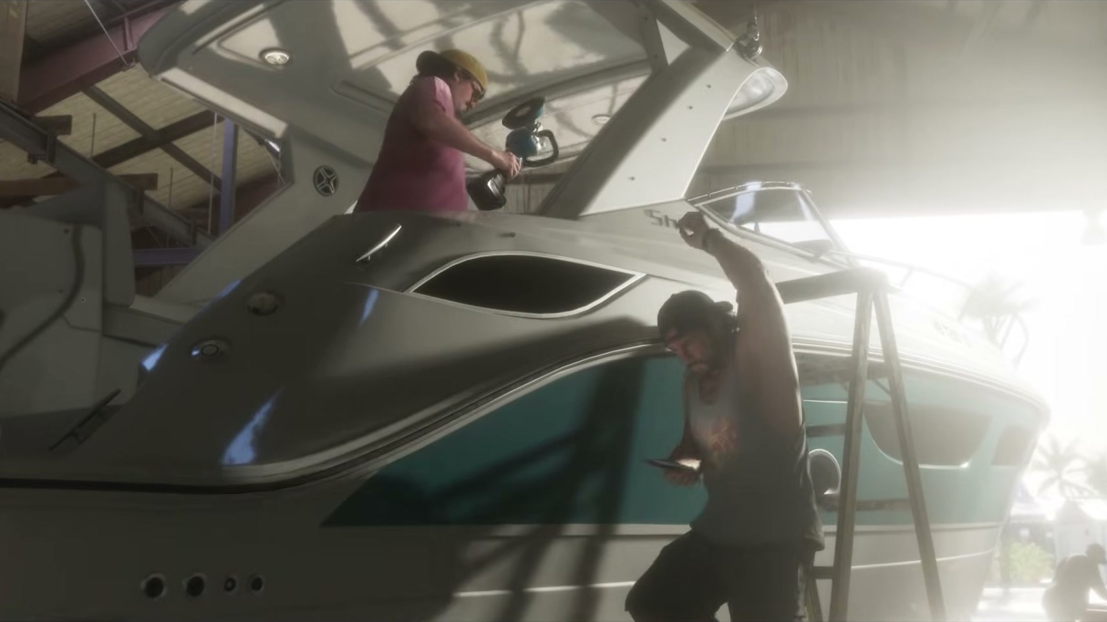 Two men work on a white yacht inside a shed, one on deck and one on a ladder.
